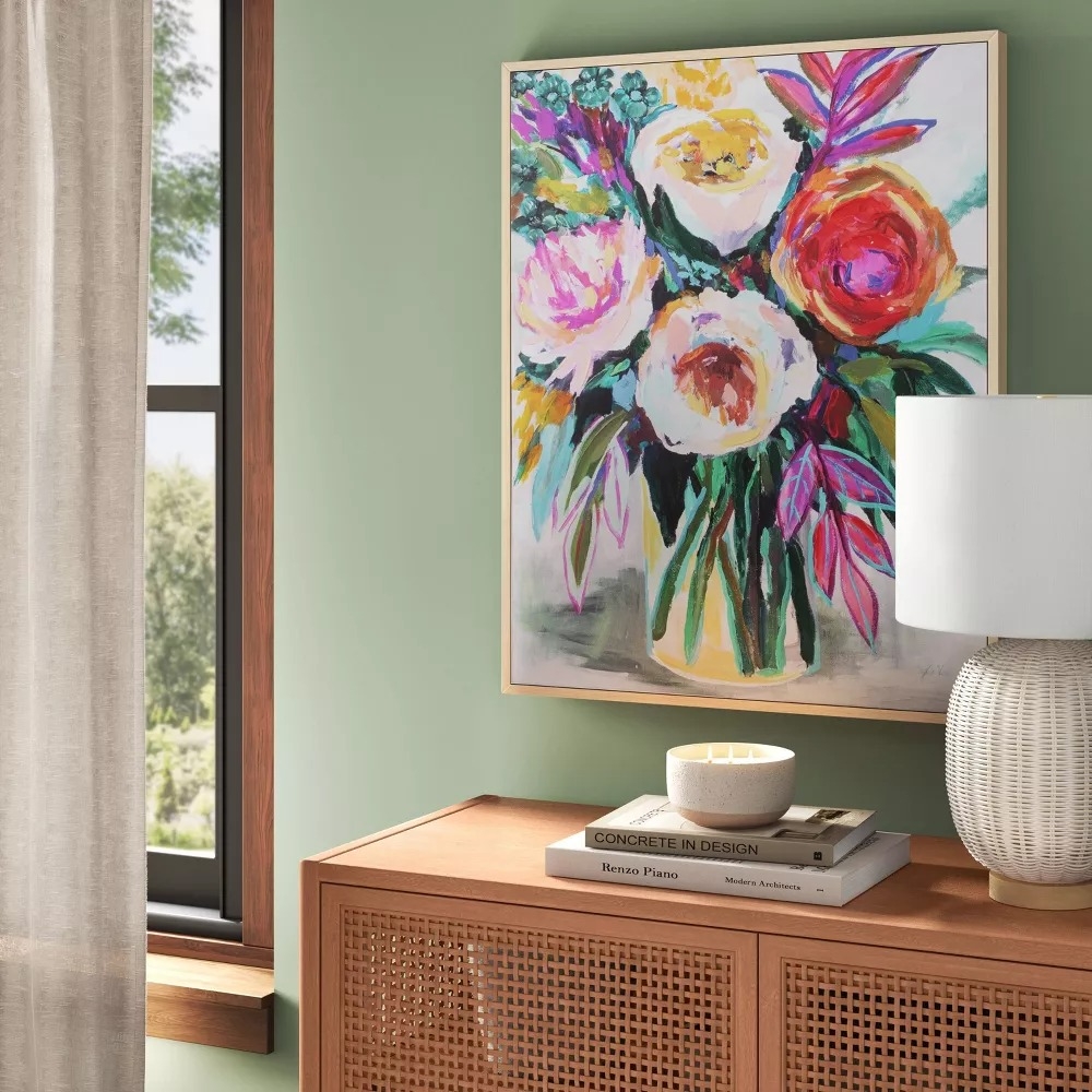A vibrant floral painting above a wooden cabinet.