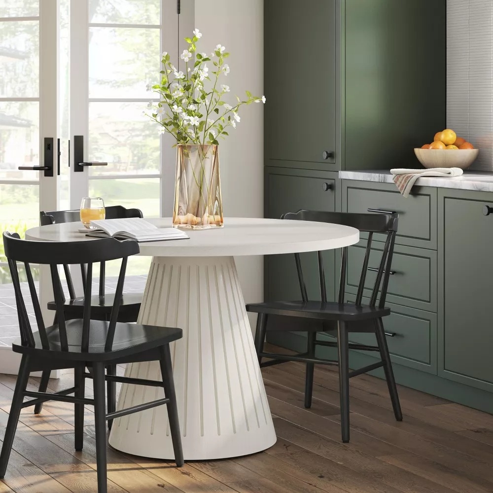 Modern kitchen with a round table and four black wooden dining chairs.