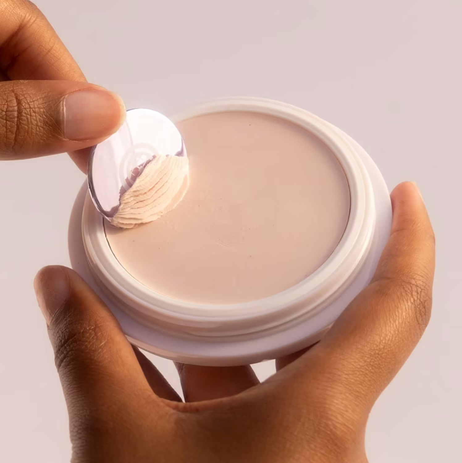 model scooping Tatcha Silk Canvas primer out of container