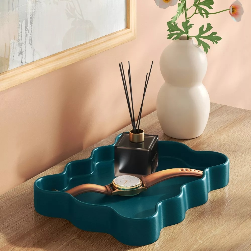 Watch and reed diffuser on a wavy teal tray.